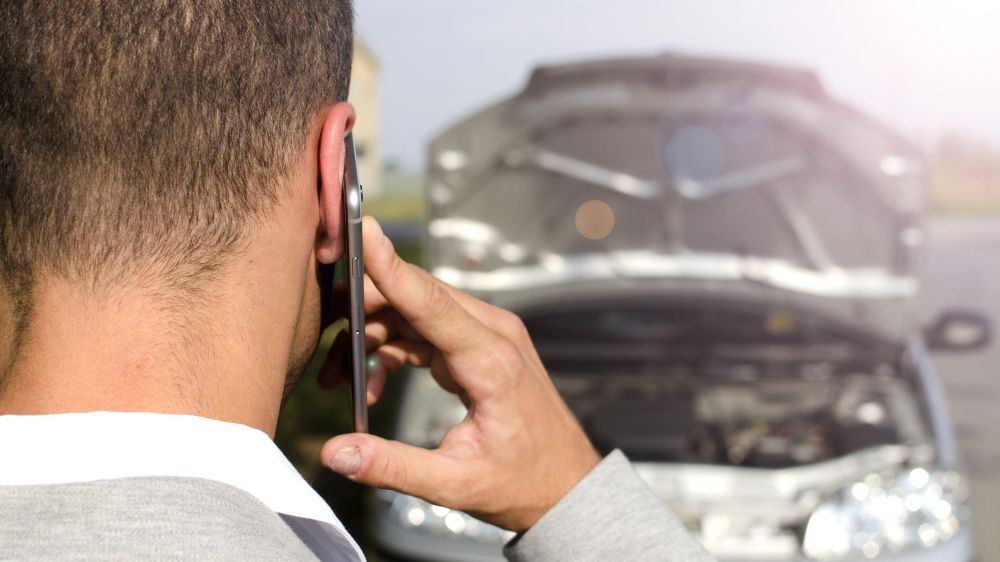 image shot from behind of a man in a car accident talking on the phone after a crash