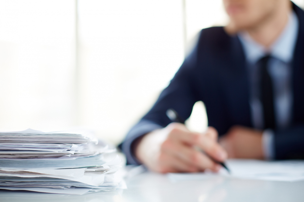 close up of a pile of appers with personal injury lawyer in the back working on the deposition and settlement