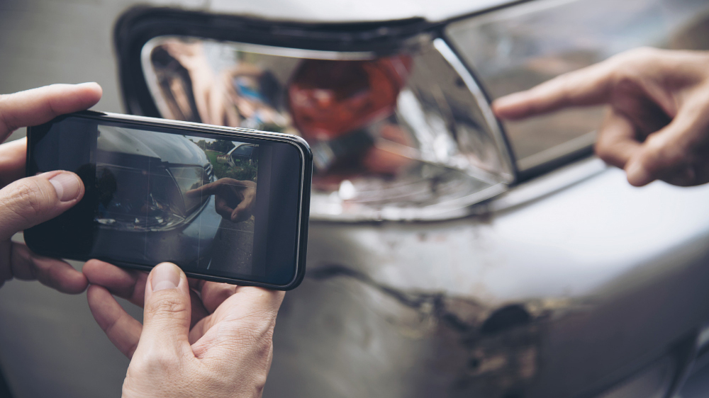 image of hands taking a picture on a phone of a minor car accident
