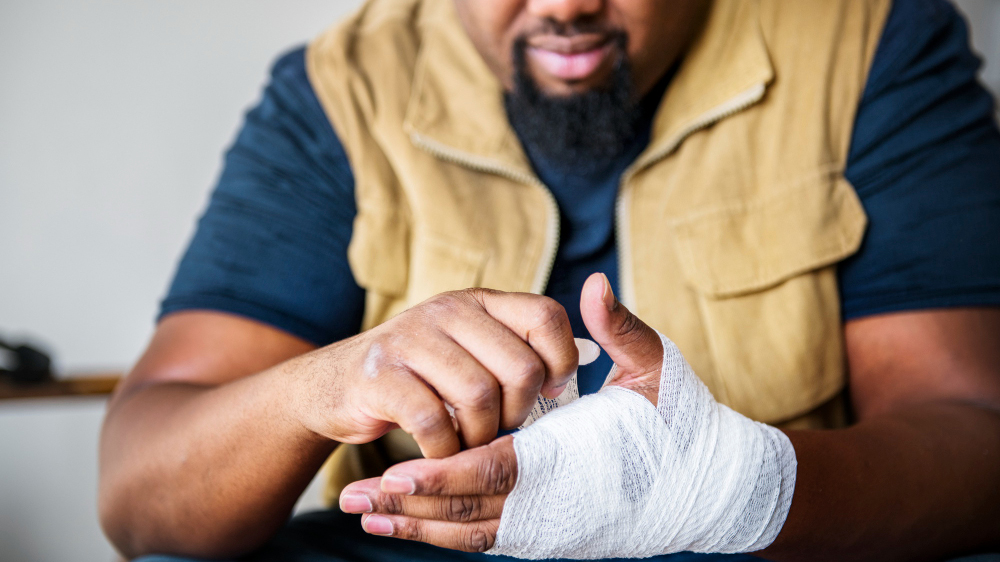 Man wrapping a bandage around his injured hand and wrist, representing how a pre-existing injury can complicate a personal injury claim.
